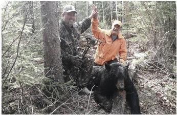 Two men in the woods with a bear.
